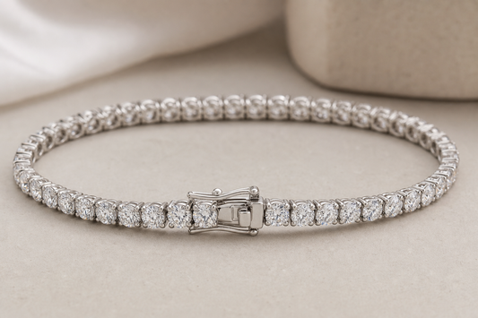 Diamond tennis bracelet on a neutral surface with visible clasp and stone settings
