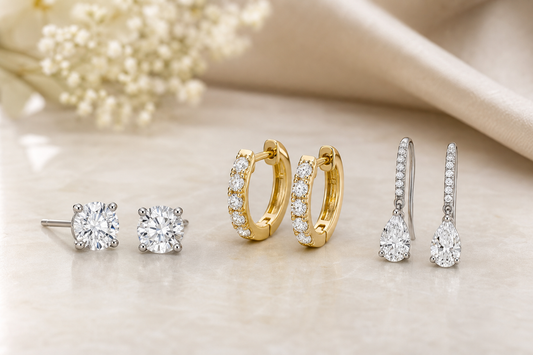 Diamond stud, hoop, and drop earrings arranged on a neutral surface