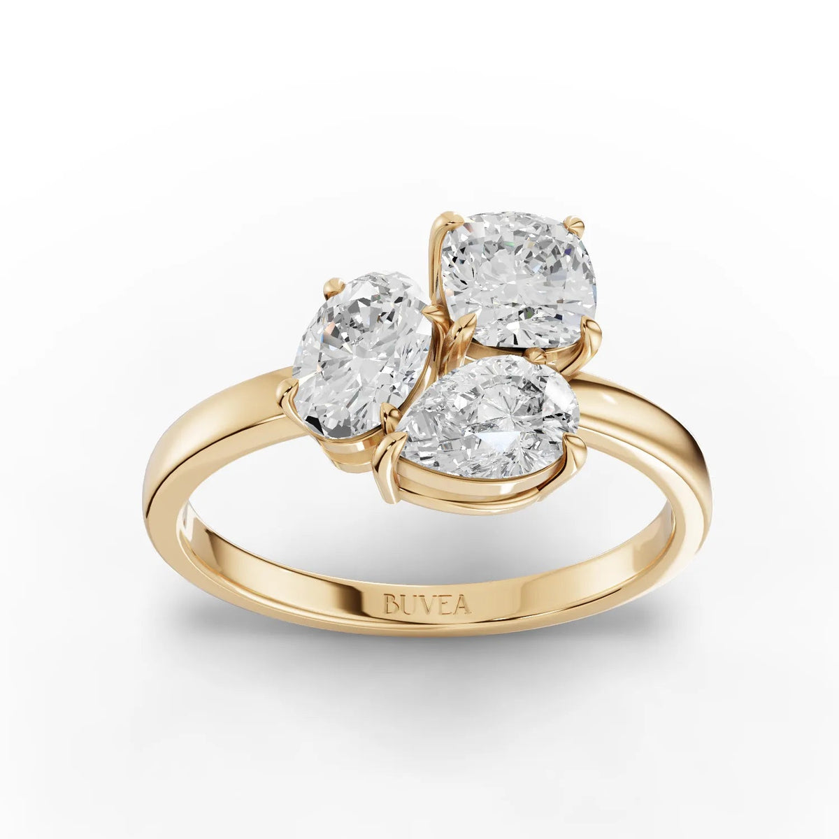 Three-stone lab grown diamond ring featuring an oval center, cushion-cut, and pear-shaped diamonds set in 18K gold.