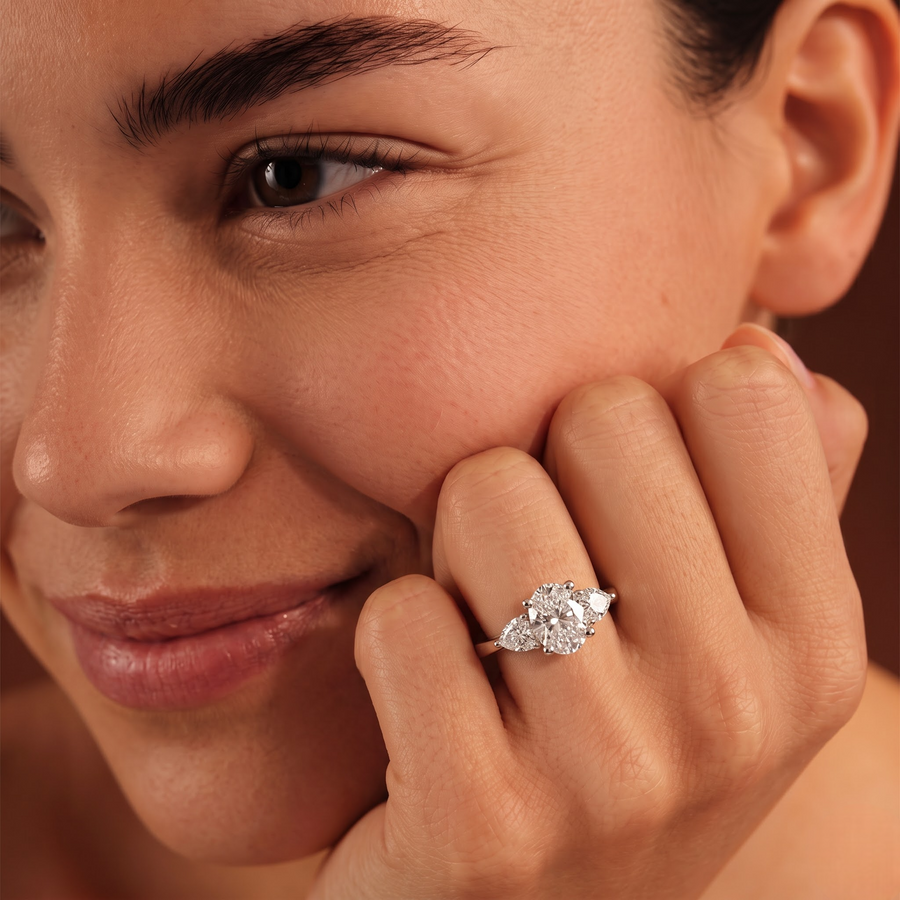 1.50 Ct oval three stone lab diamond ring in 18K gold, featuring a 1 CT oval center and two heart-shaped side stones.