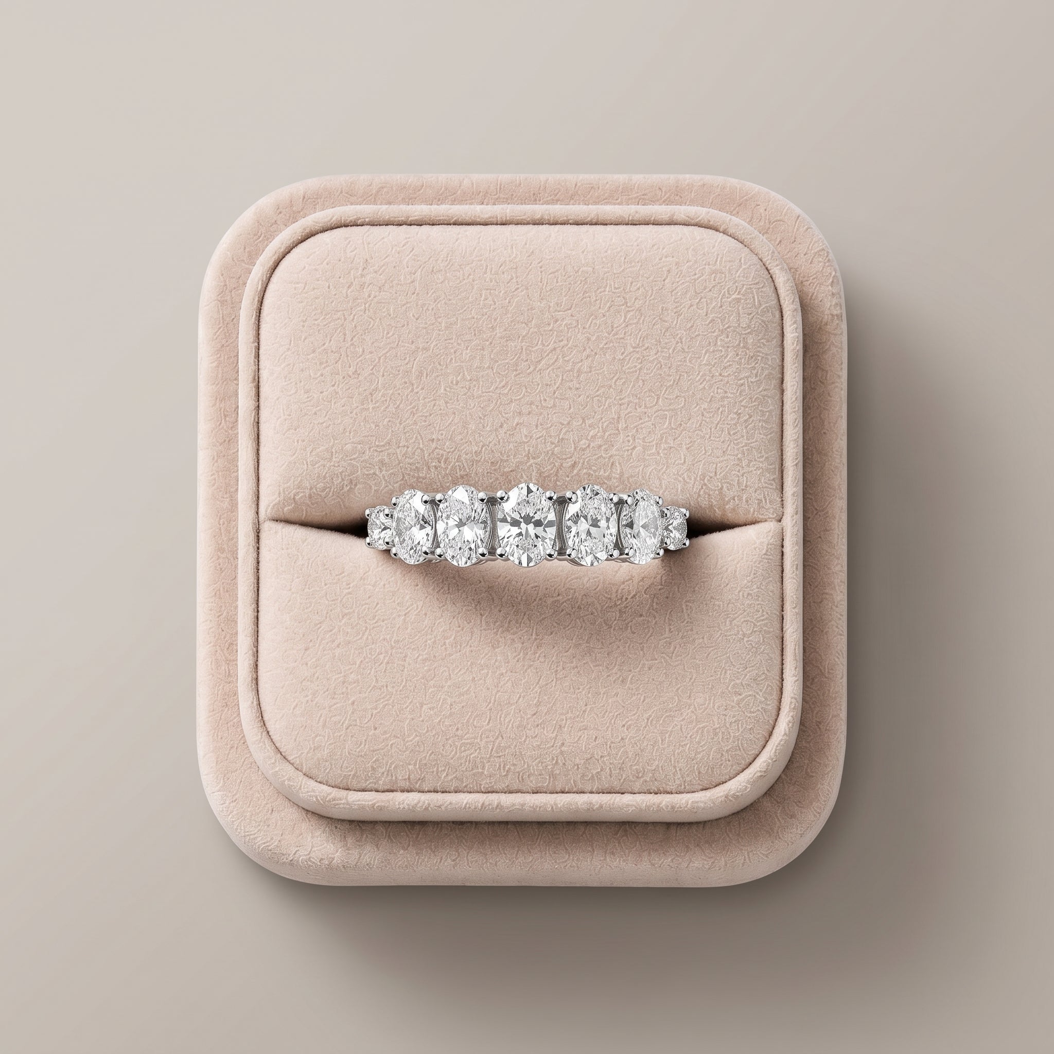 1.13 Ct oval half eternity lab diamond ring with a row of oval and round diamonds, set in 18K gold, on a soft display.