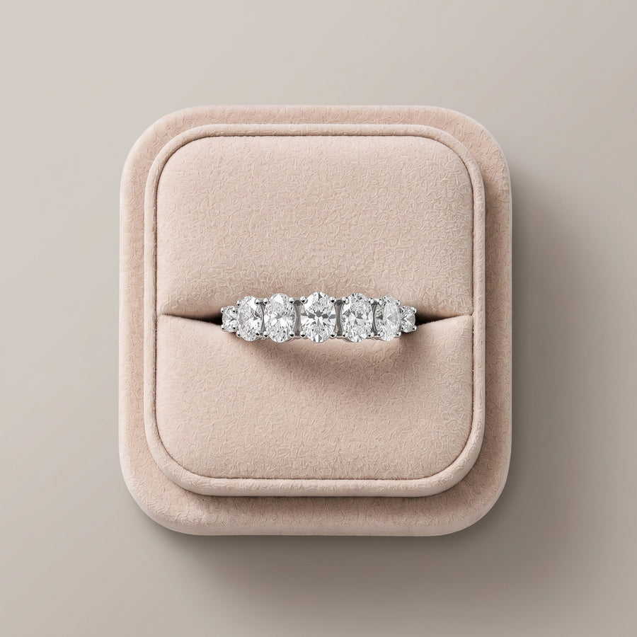 1.13 Ct oval half eternity lab diamond ring with a row of oval and round diamonds, set in 18K gold, on a soft display.