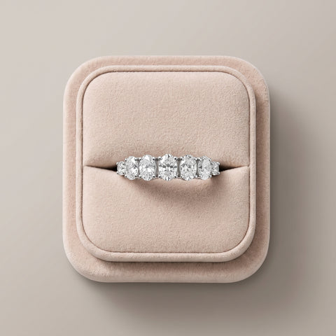 1.13 Ct oval half eternity lab diamond ring with a row of oval and round diamonds, set in 18K gold, on a soft display.
