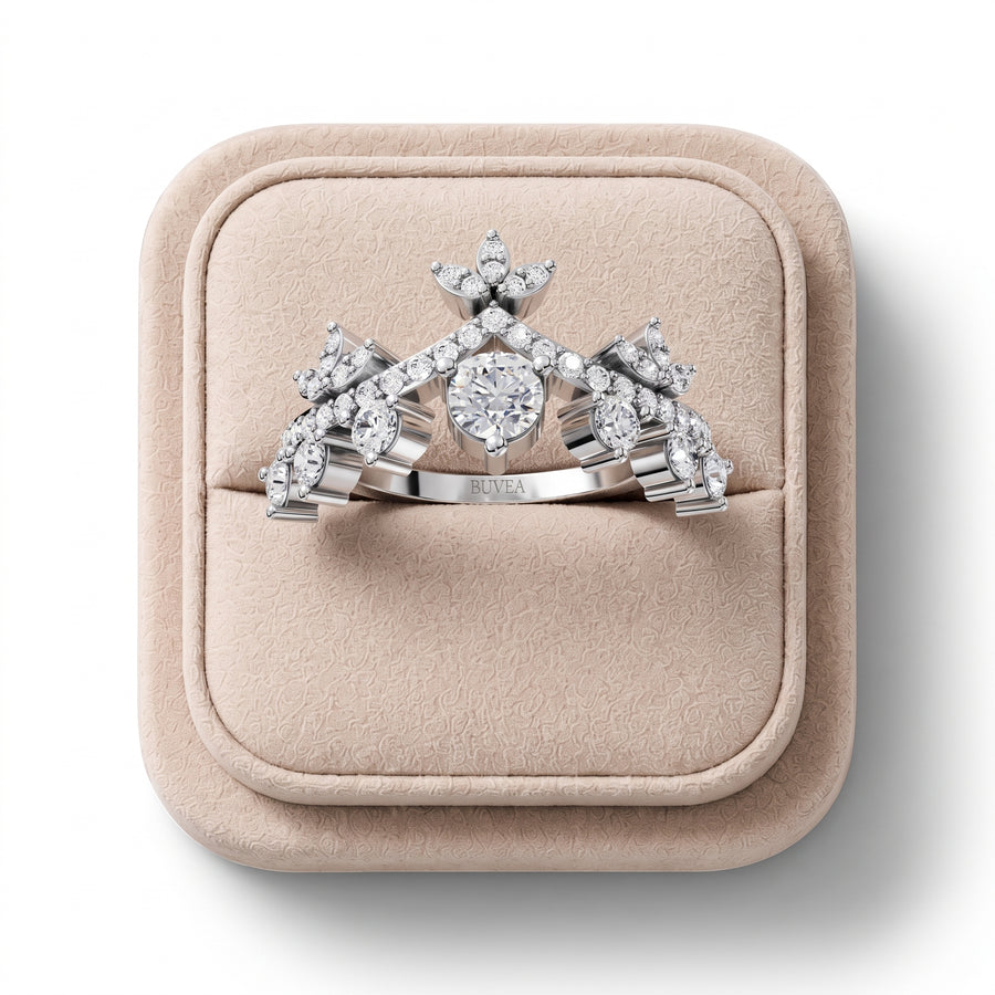 Crown-style lab diamond ring featuring a round center stone, surrounded by accent stones in a floral motif. Set in white metal.