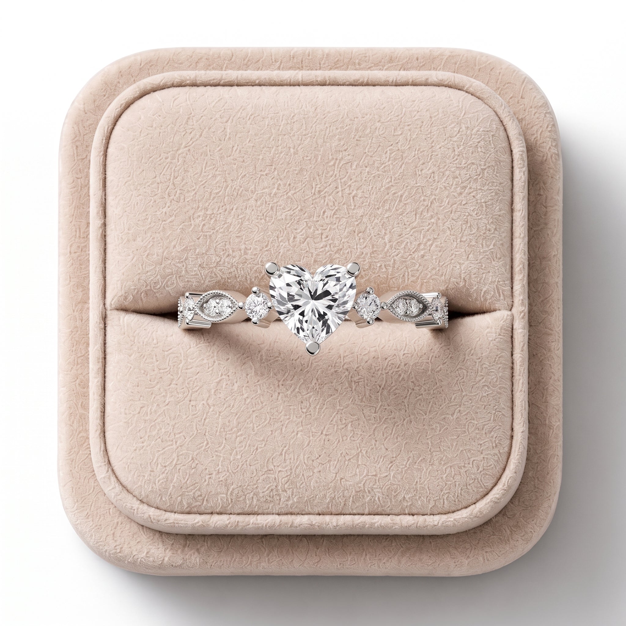 Heart-shaped lab diamond ring with round accent diamonds, milgrain detail, and a tapered band, displayed on a soft jewelry box.